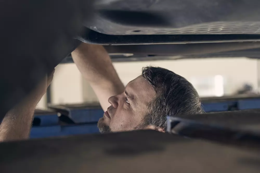 Kevin Müller bei einer Reparatur am Fahrzeugunterboden